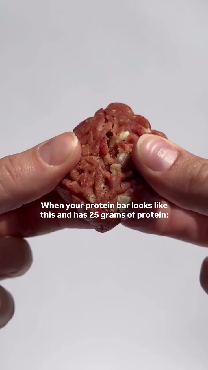Hands break open a Strawberry Blondie to show its soft, strawberry-speckled texture.