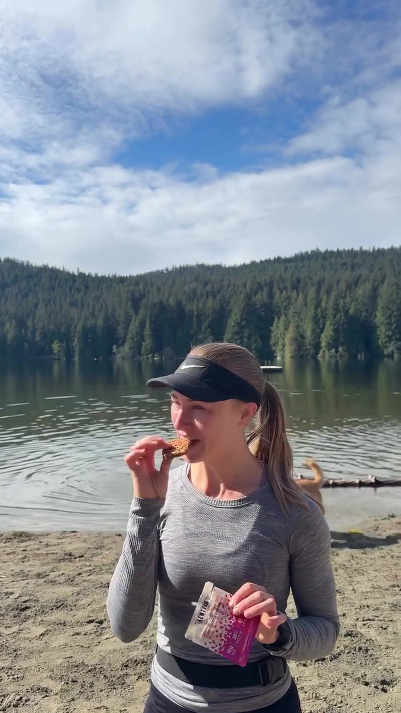 Run-club members taste Honey Peanut Crispy, Salted Double Cacao and Almondy Raspberry Elite Squares beside a lake.