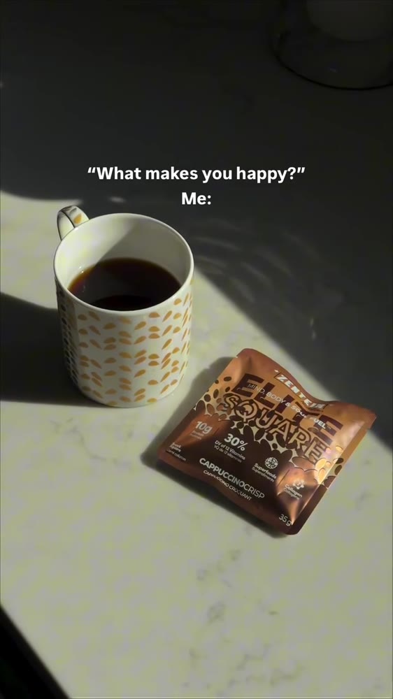 A mug of coffee and a Cappuccino Crisp Elite Square on a sunlit table.